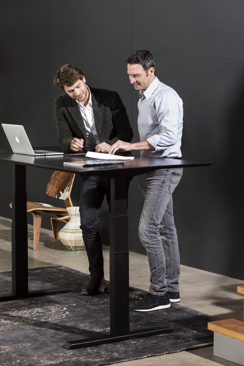 Twee mannen aan een zwart zit-sta bureau